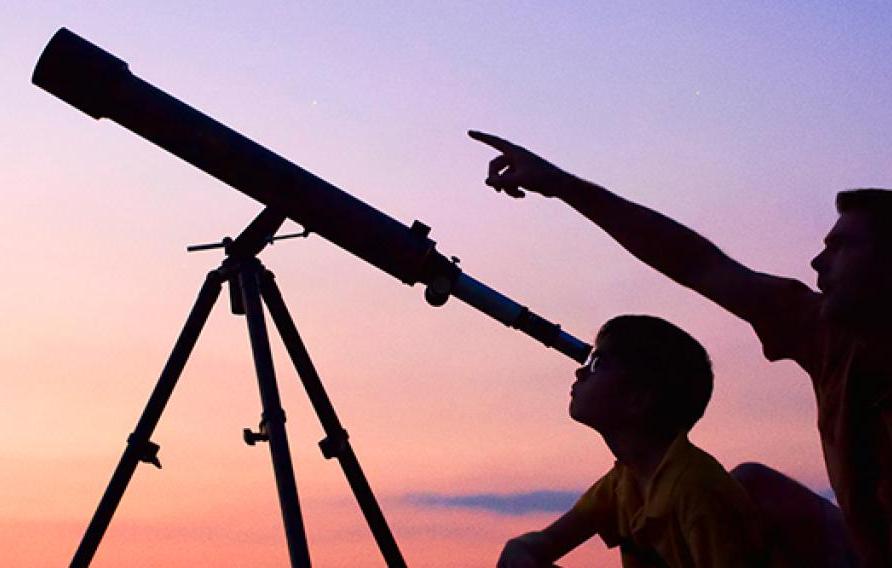 Man and son looking through telescope at dusk